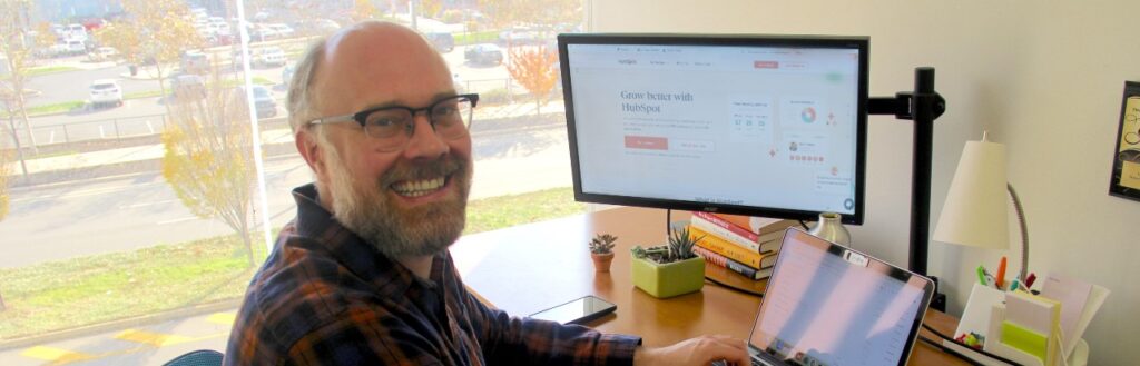 smiling marketing account manager using hubspot CRM in an office