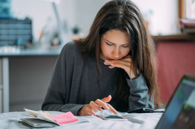 woman looking at mobile phone on desk