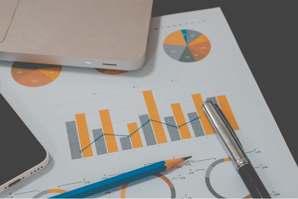 A laptop sits next to graphs and pie charts.