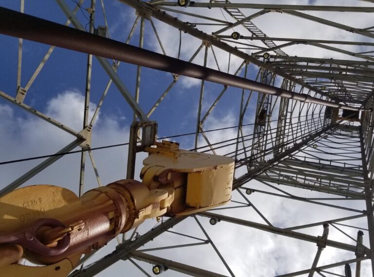 Looking up towards the sky under a drilling structure.