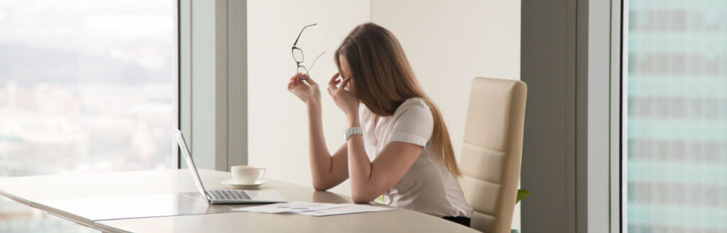 irritated woman sitting at desk with laptop open