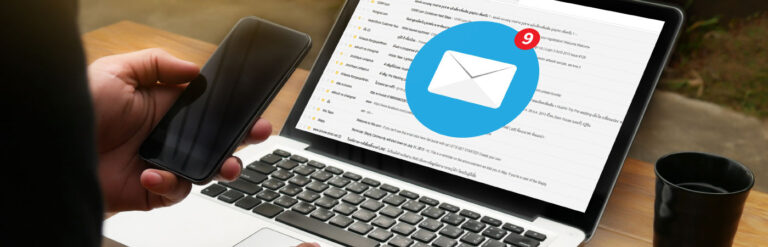 person holding iphone and looking at their email on laptop