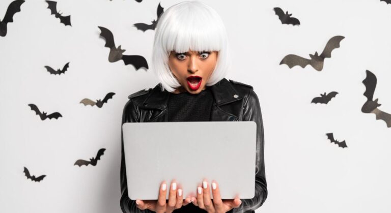 shocked woman in white wig looking at laptop with bats in the background