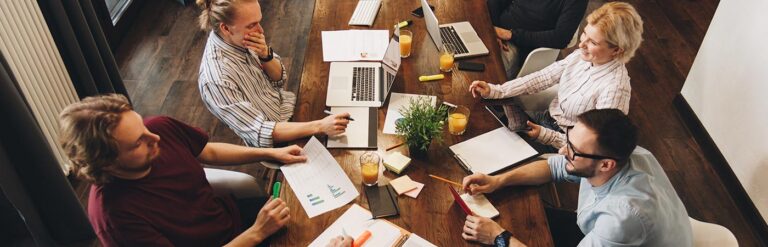 digital marketing agency meeting at table with metrics and laptops
