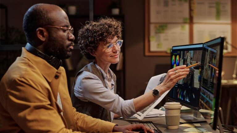 two video editors pointing at a computer screen with a video editing tool open