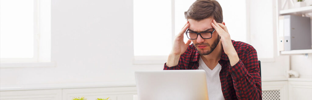annoyed man with glasses frowning at laptop