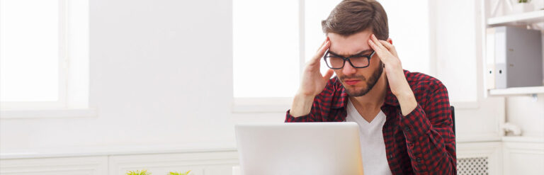 annoyed man with glasses frowning at laptop