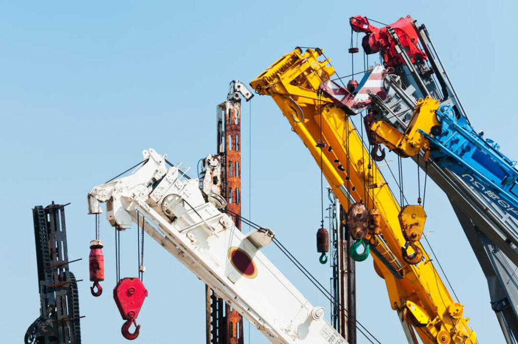 A group of mobile cranes with hooks and pulleys, dockyard lifting equipment.