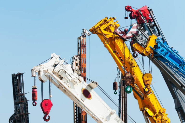 A group of mobile cranes with hooks and pulleys, dockyard lifting equipment.