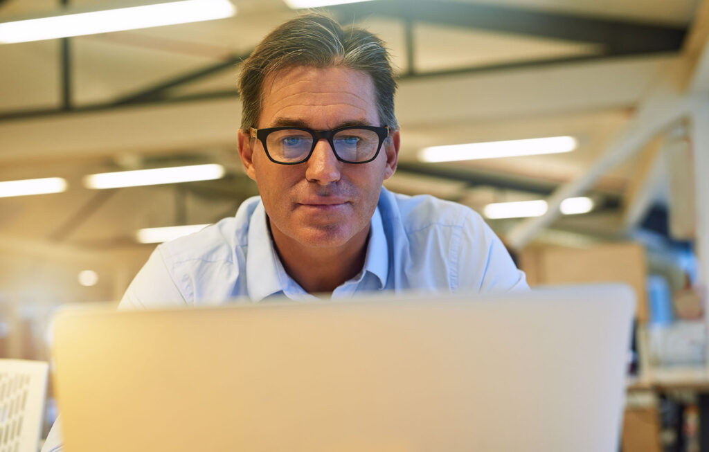 middle aged man focused on laptop in office